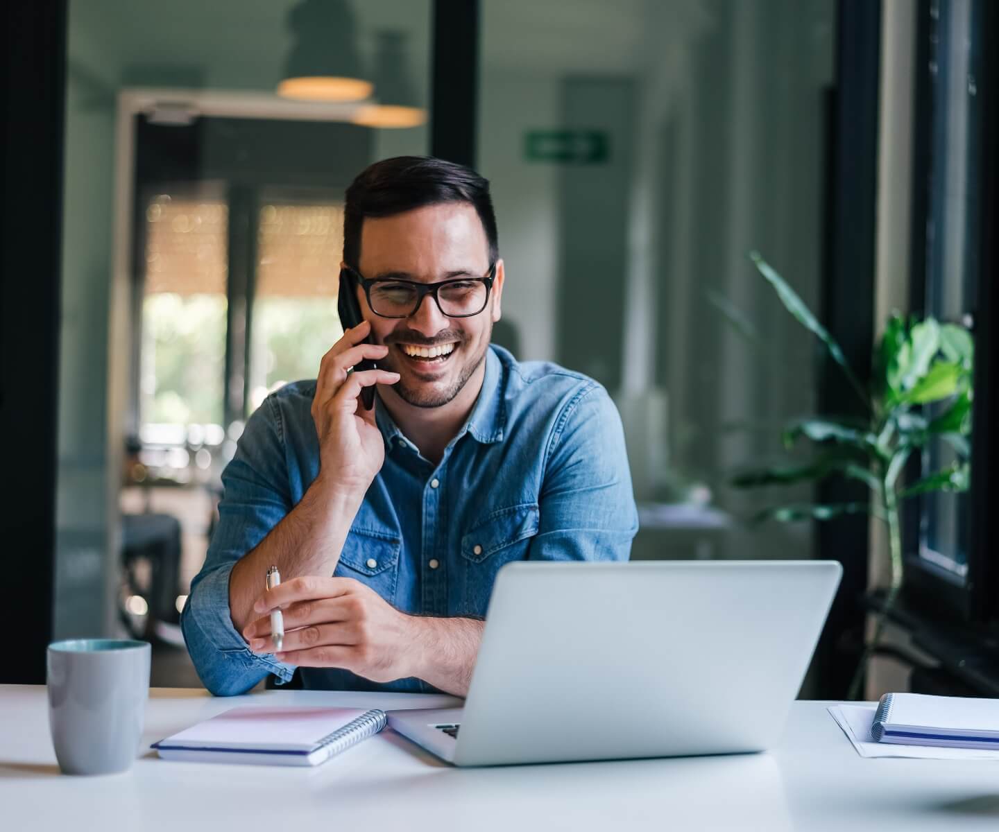 man smiling behind laptop at desk